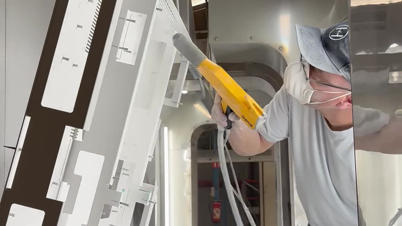 Peintre Duflot appliquant la finition sur une pièce métallique dans le tunnel de peinture convoyé à Holnon (Aisne, Hauts-de-France)